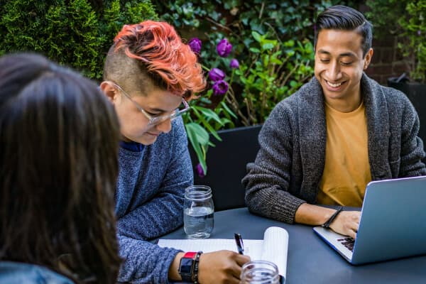 A group of case managers collaborating at a table, with a laptop and papers in front of them.