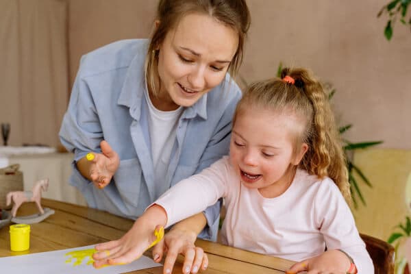 A therapist finger painting with a young child with disabilities.